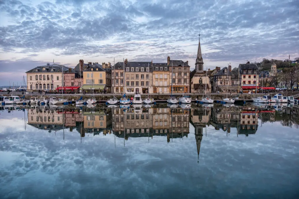 Port De Honfleur Avec Les Batiments Refletant Sur L Eau Sous Un Ciel Nuageux En France 